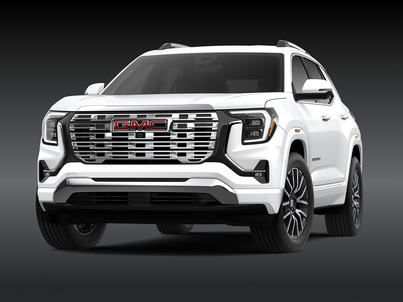 A Front Three-Quarter View of the White 2026 2027 GMC Terrain Denali SUV on a Dark Background.