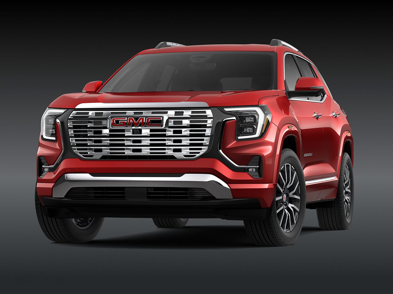A Front Three-Quarter View of the Red 2026 2027 GMC Terrain Denali SUV on a Dark Background.