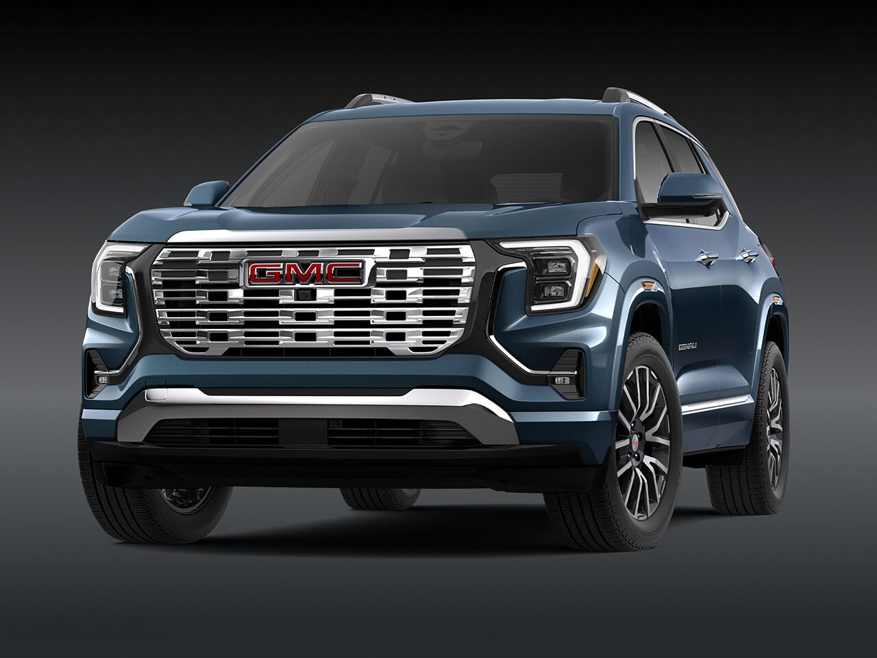 A Front Three-Quarter View of the Dark Blue 2026 2027 GMC Terrain Denali SUV on a Dark Background.