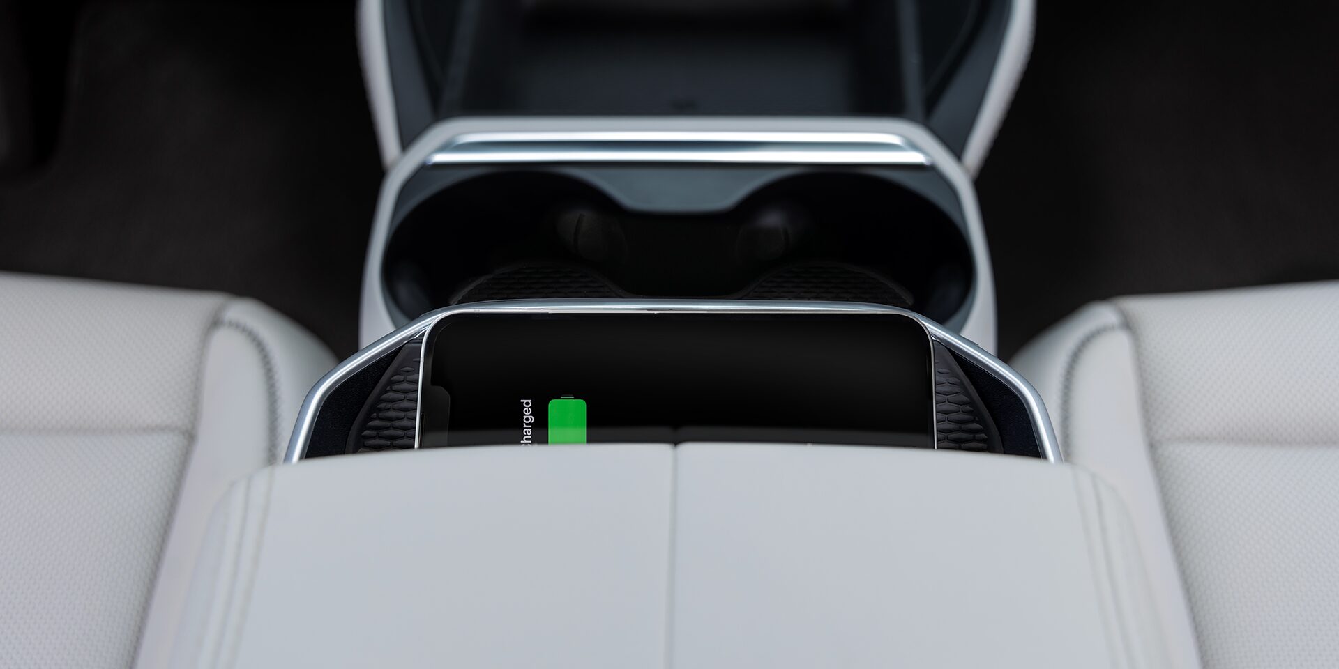 A Smartphone is Wirelessly Charging in the Center Console of a 2027 GMC Terrain Vehicle with Light Colored Seats.