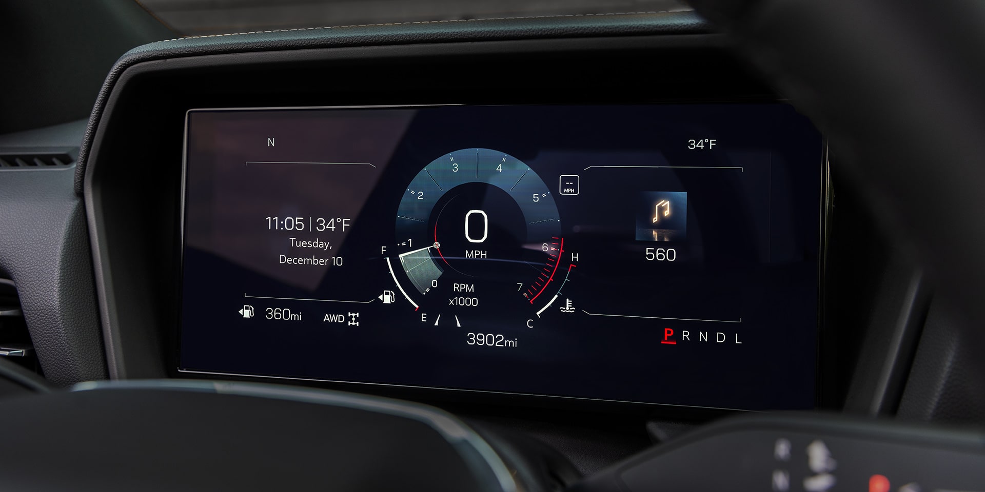 Un gros plan du tableau de bord numérique d’un GMC Terrain 2027 derrière le volant, affichant vitesse, temps, température, kilométrage et vitesse.