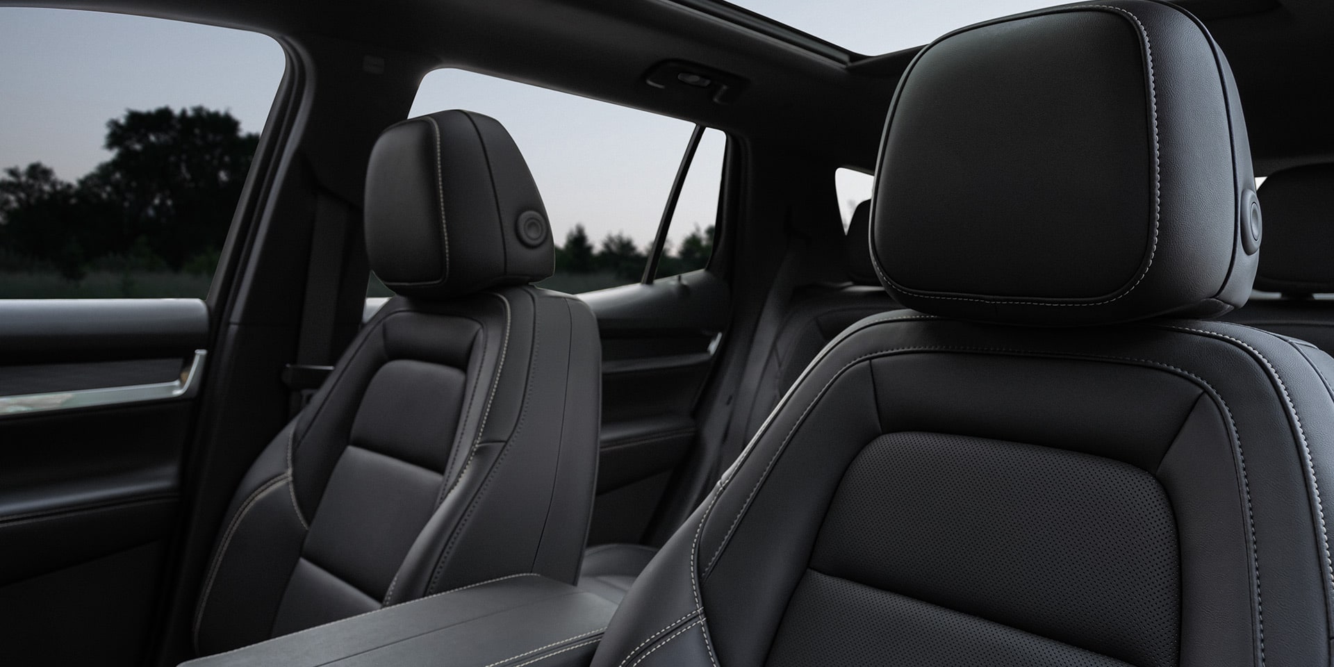 Vue intérieure des sièges passager avant en cuir noir d’un GMC Terrain 2027, surpiqûres blanches et toit ouvrant panoramique.