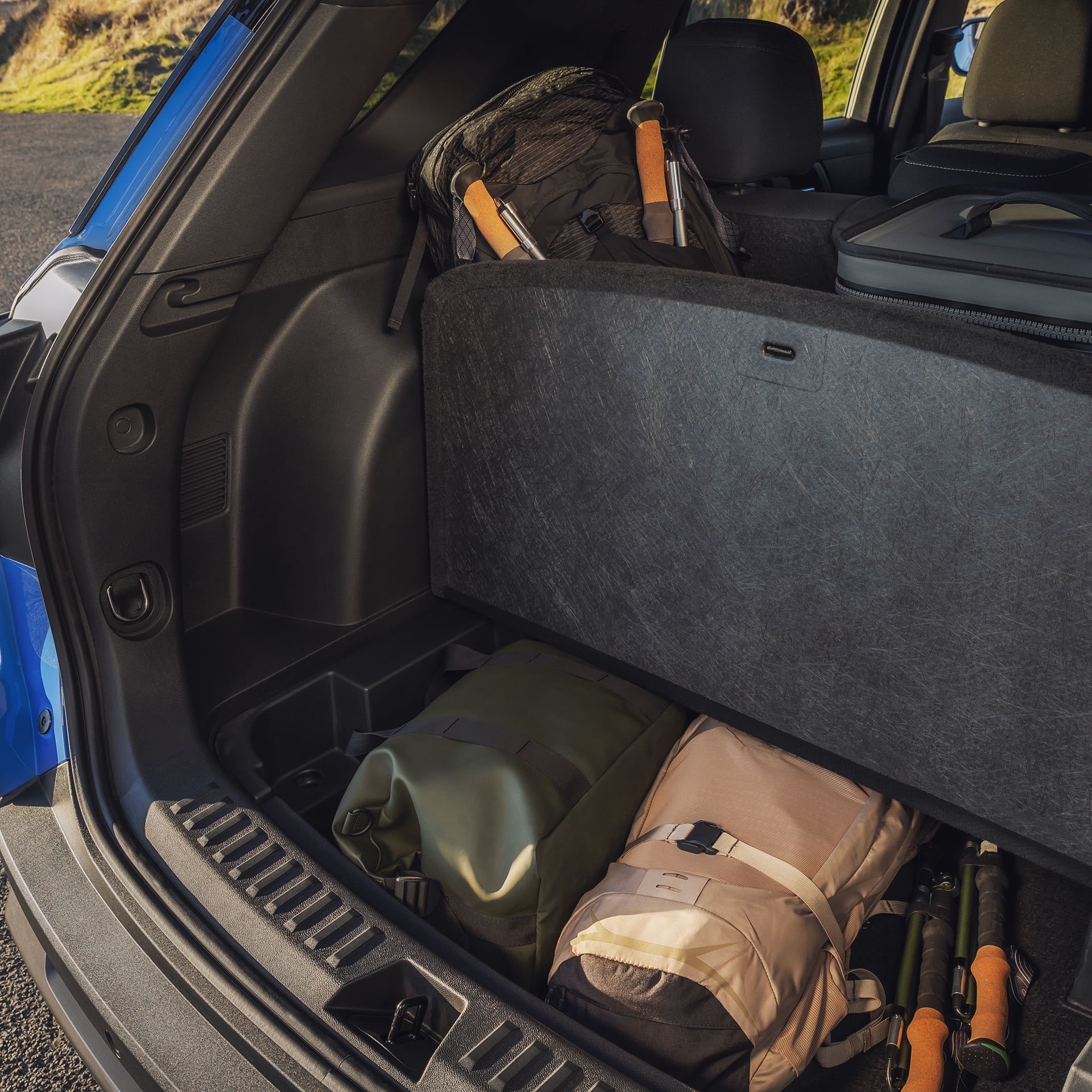 L’espace de chargement ouvert d’un SUV GMC Terrain bleu 2027, rempli de sacs et de bâtons de trekking.