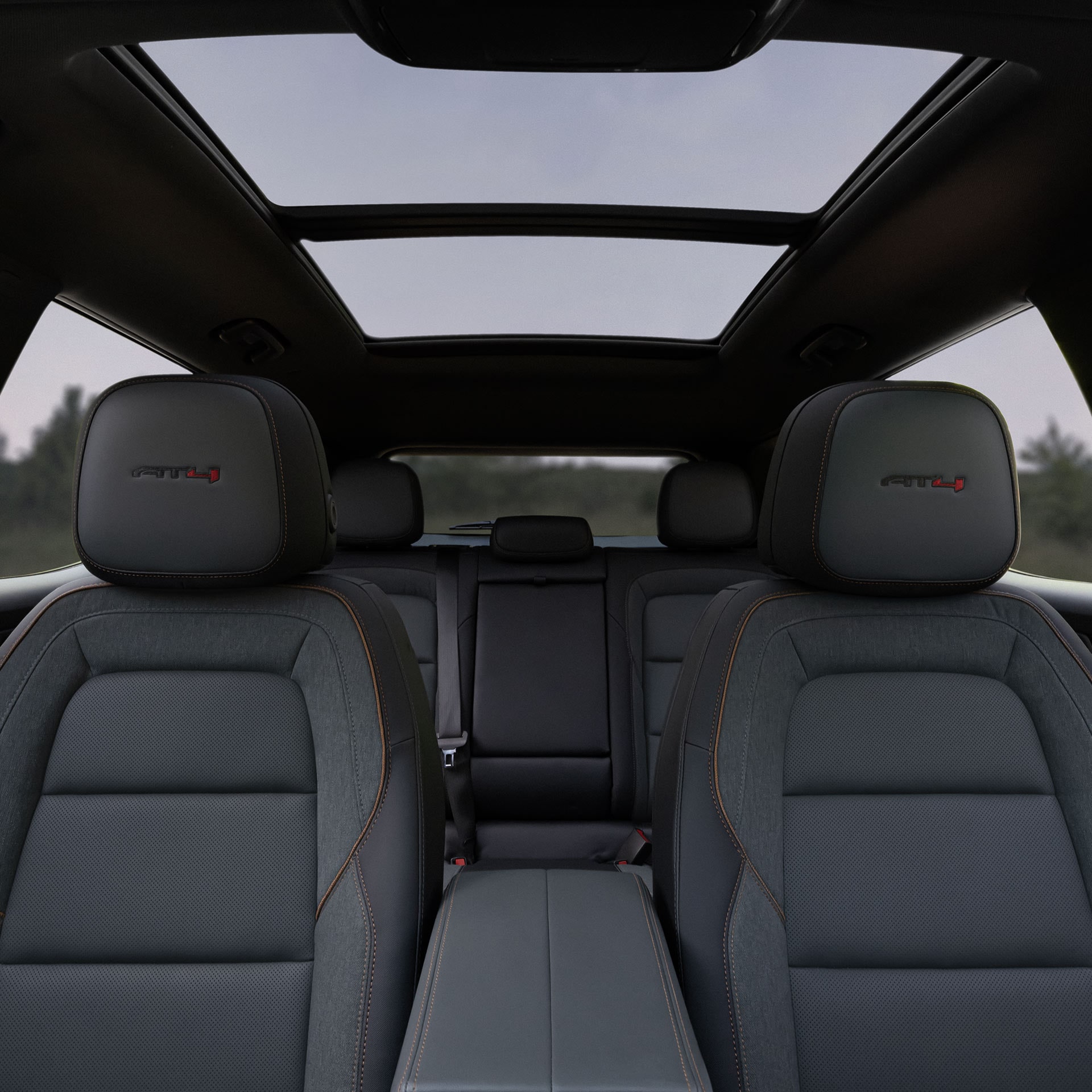 Une vue intérieure des sièges arrière d’une GMC Terrain AT4X 2027 avec les logos AT4X sur les appuie-têtes et un toit ouvrant panoramique.