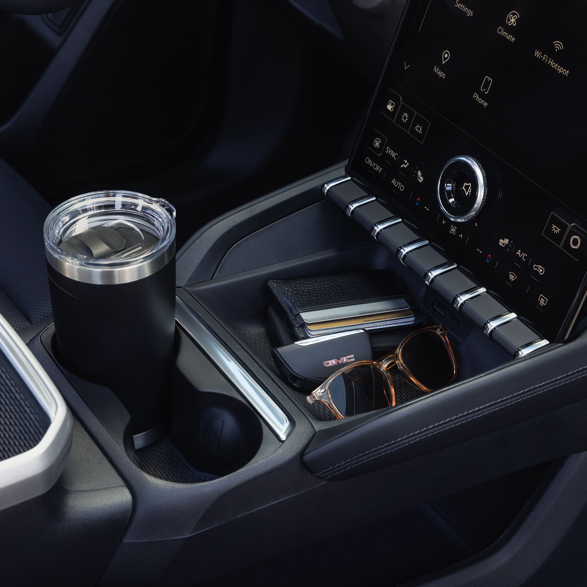 La console centrale d’un véhicule terrain GMC 2027 affichant les porte-gobelets et objets personnels pour l’écran d’infodivertissement.