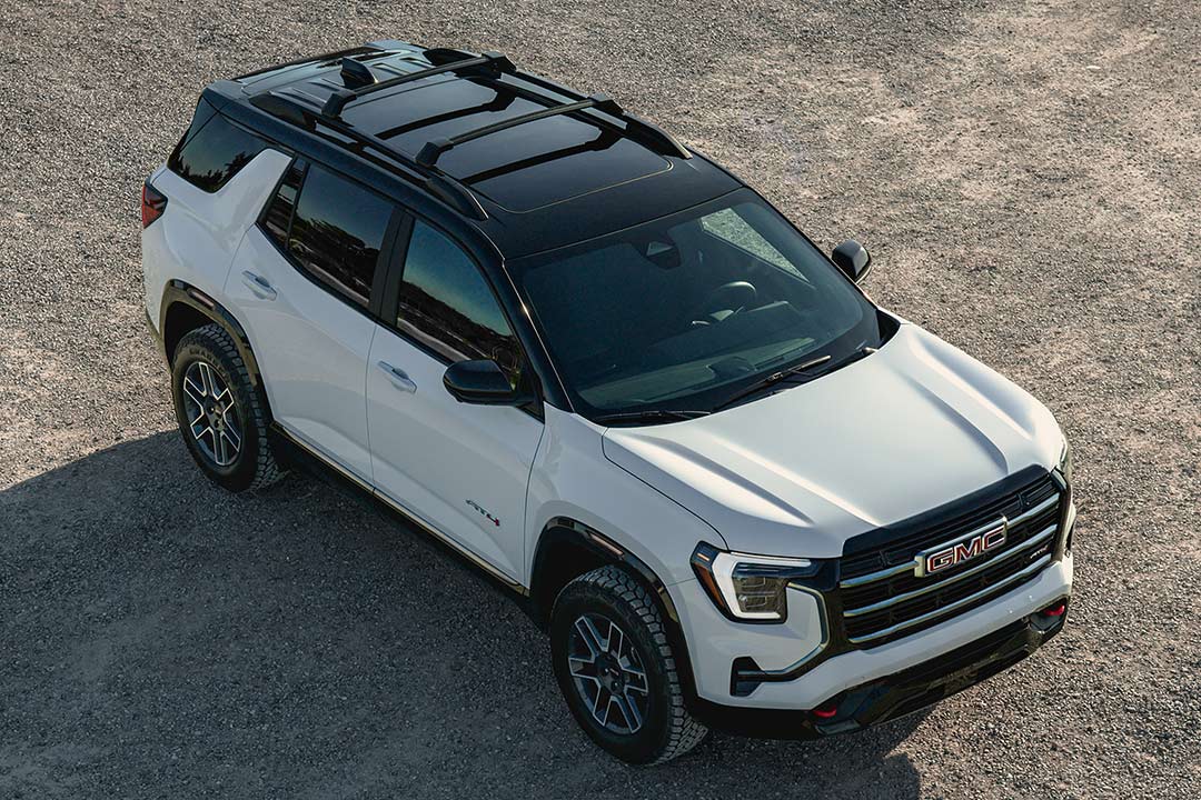 Un SUV AT4 GMC Terrain blanc 2027 avec toit noir garé sur une route de gravier.