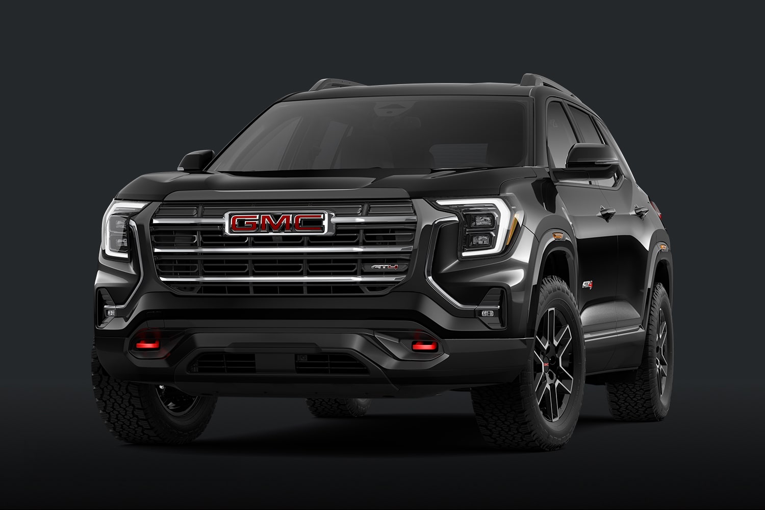 Un SUV AT4 GMC Terrain 2027 noir avec une calandre foncée et des accents rouges sur un fond sombre.
