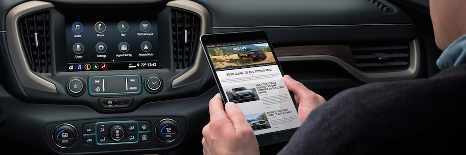 A person using an app on his phone to connect to the online services of his 2023 GMC Denali.