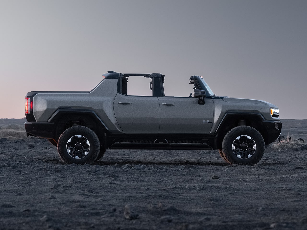 Side View of the 2026 GMC Hummer EV Pickup Truck Parked in a Rocky Desert.
