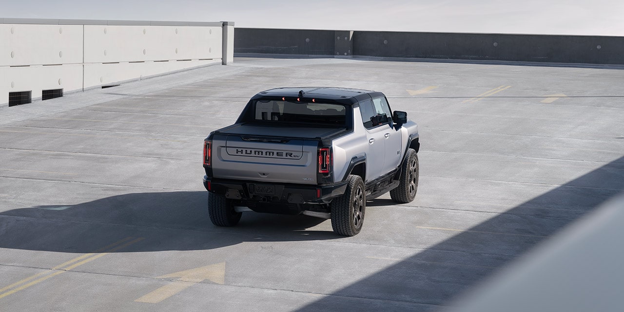 Bird's Eye View of the Rear End of a 2026 GMC Hummer EV Pickup Truck Parked on the Top Level of a Parking Garage.