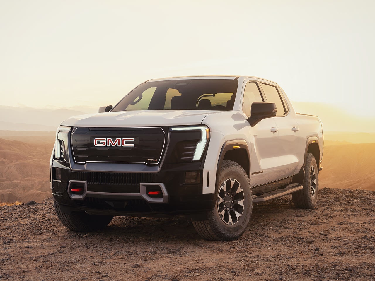 Le GMC Sierra EV 2026 stationné dans le désert et scintillant sous le soleil.