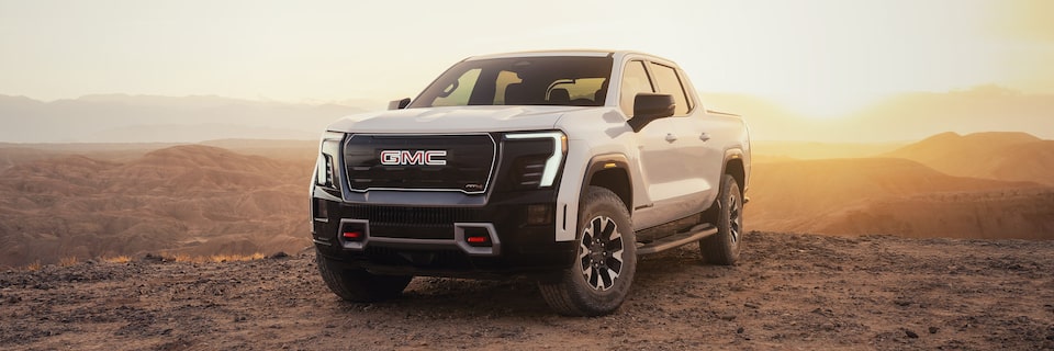 Le GMC Sierra EV 2026 stationné dans le désert et scintillant sous le soleil.
