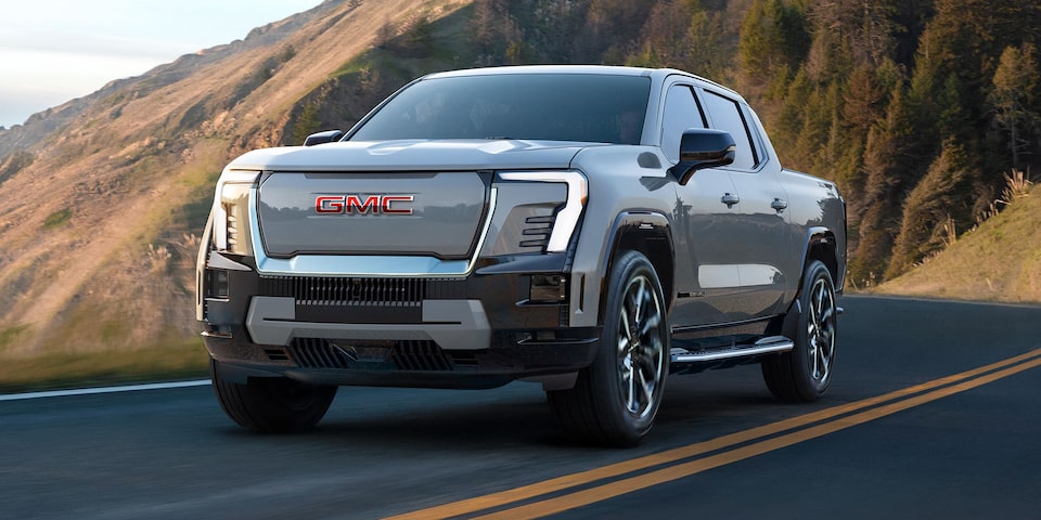 Le pick-up GMC Sierra EV 2026 en mouvement seul sur une route de montagne.