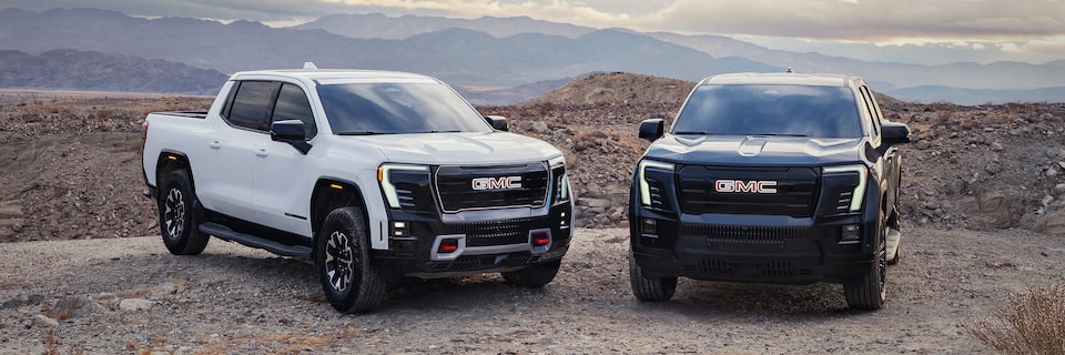 Deux pick-up GMC Sierra EV 2026 stationnés sur une montagne rocheuse.