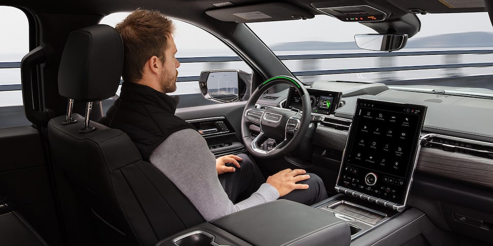Une personne conduit le GMC Sierra EV 2026 sans les mains avec l’aide de la technologie Super Cruise.