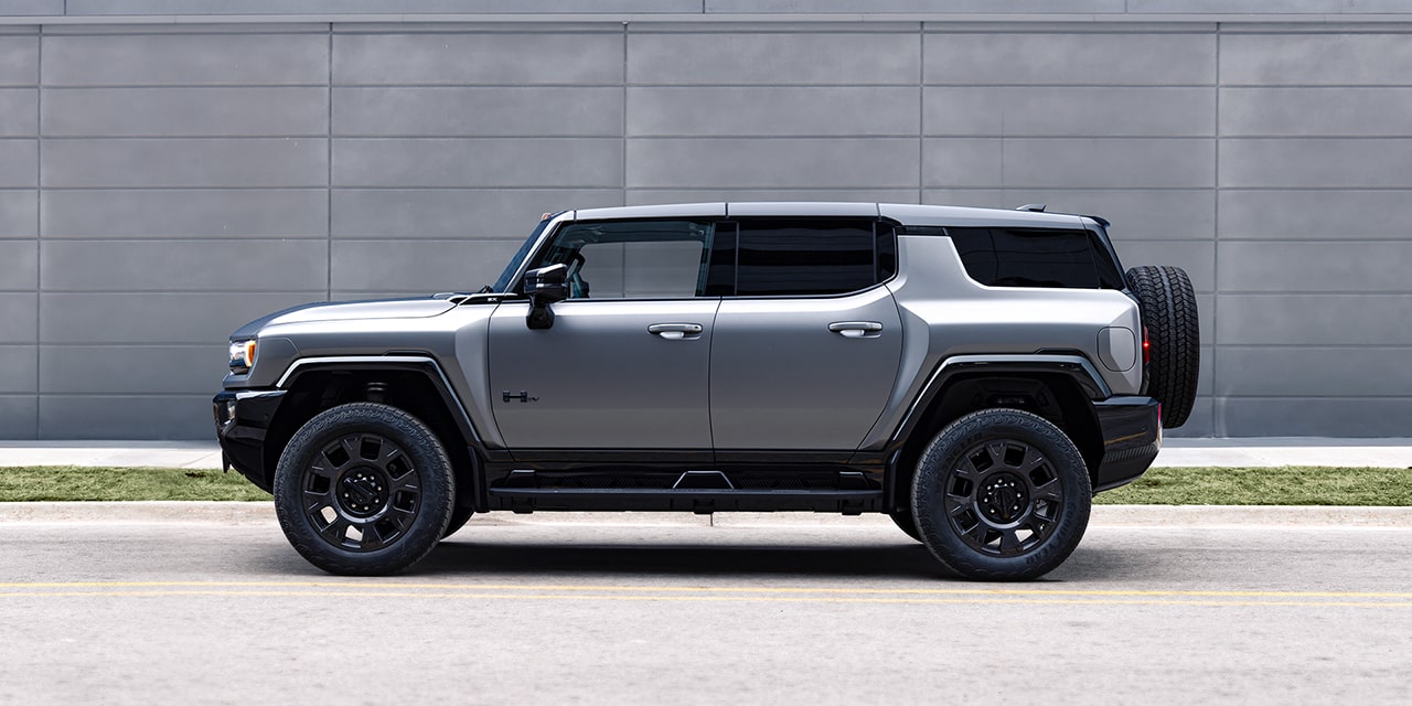Vue latérale du VUS GMC Hummer EV 2026 stationné seul devant un mur de béton.