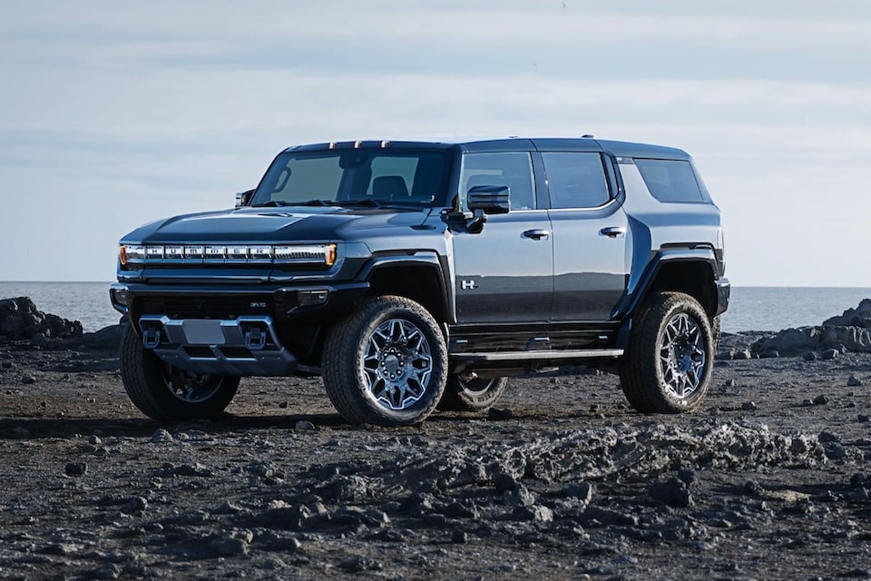 Vue latérale avant du pick-up GMC Hummer EV 2025 à la tombée de la nuit.
