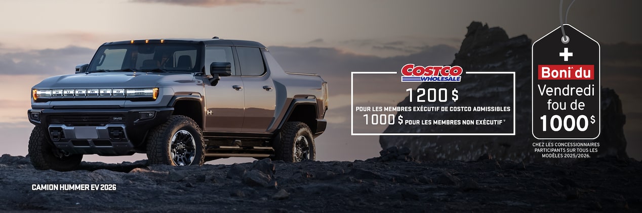 Vue latérale avant du camion GMC Hummer EV 2026 stationné au sommet d’une montagne rocheuse au coucher du soleil.
