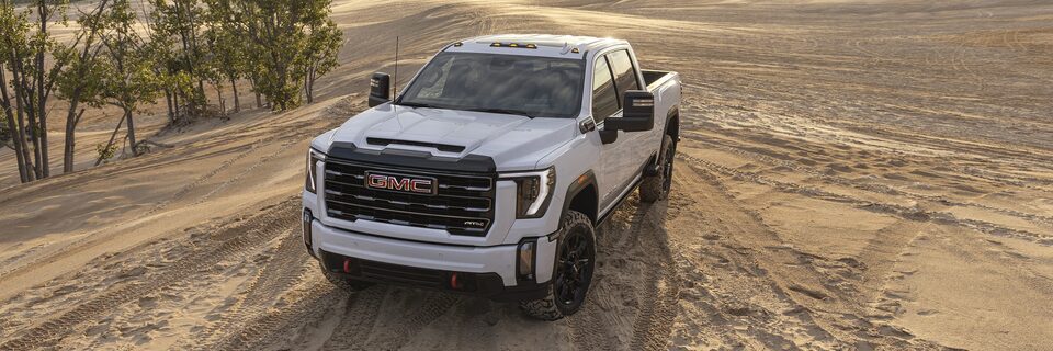 2024 Sierra HD AT4 surrounded by tire tracks in the sand.