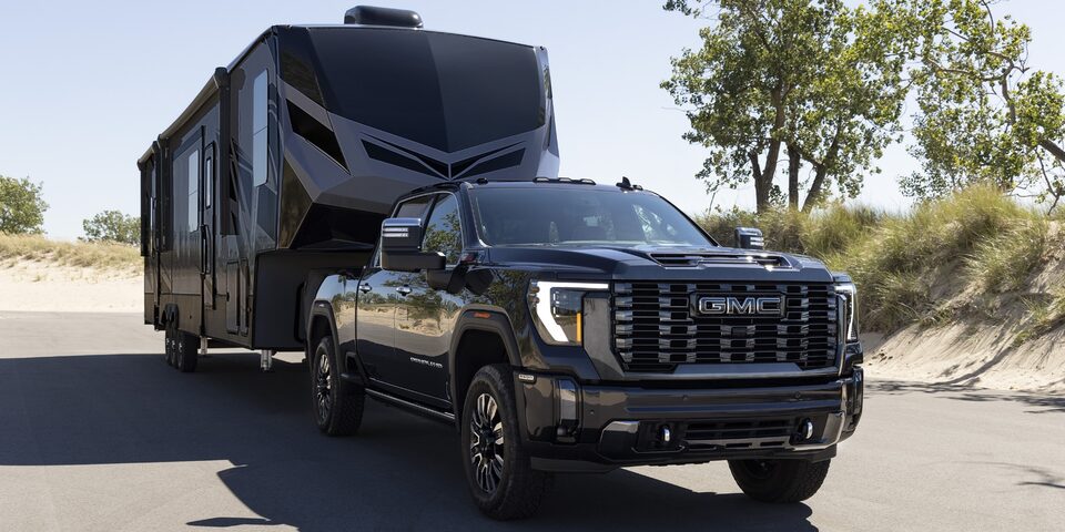 Front right profile view of the 2024 GMC Sierra HD while towing a trailer.