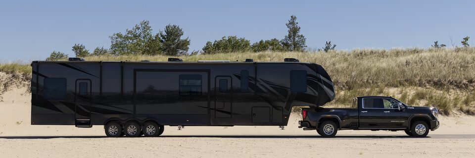 Full right side view of the 2024 GMC Sierra HD towing a trailer through the desert.