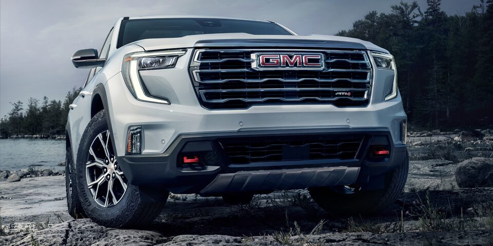 Vue en contre-plongée du GMC Acadia AT4 2024 stationné au bord d’un lac.