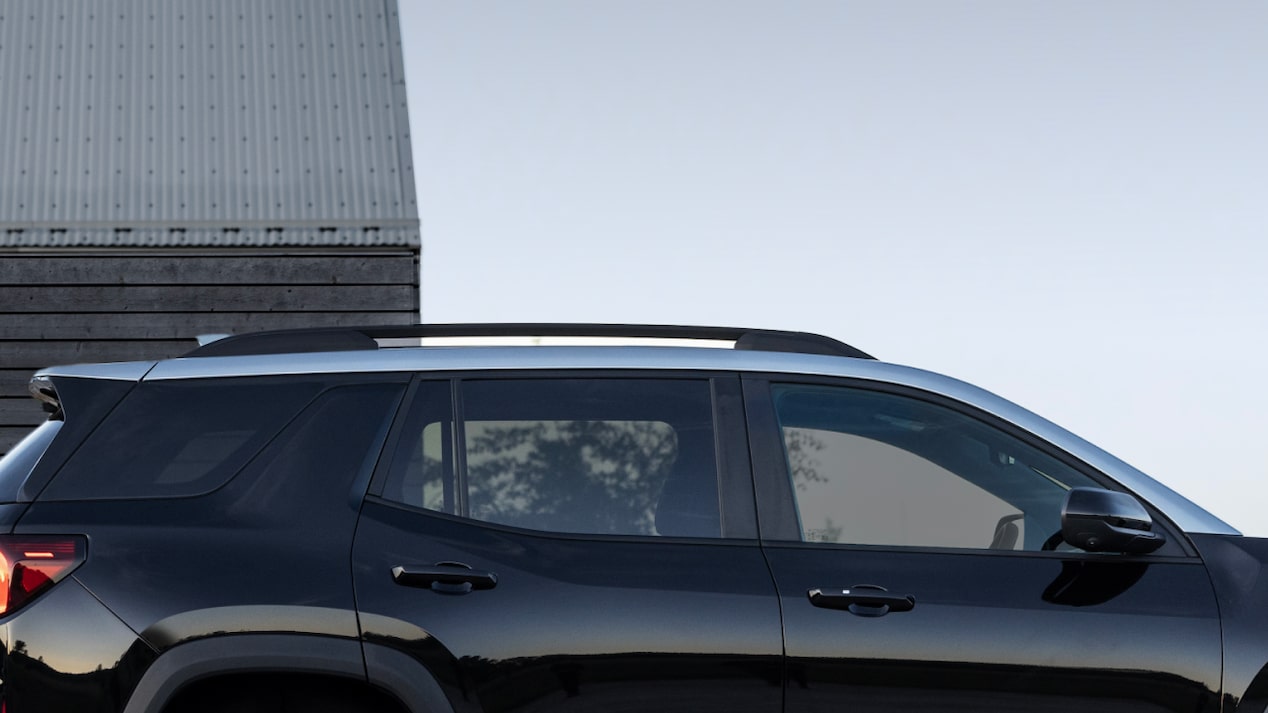 Side view of the 2025 GMC Terrain parked outside a wooden structure.