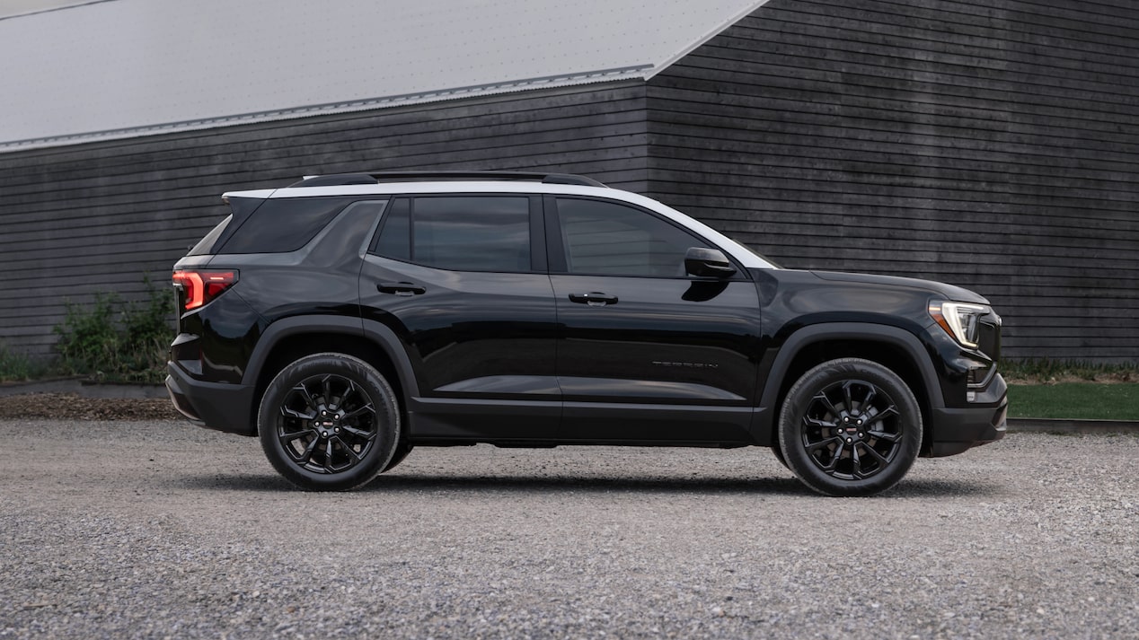 Side view of the 2025 GMC Terrain parked beside a wooden building.