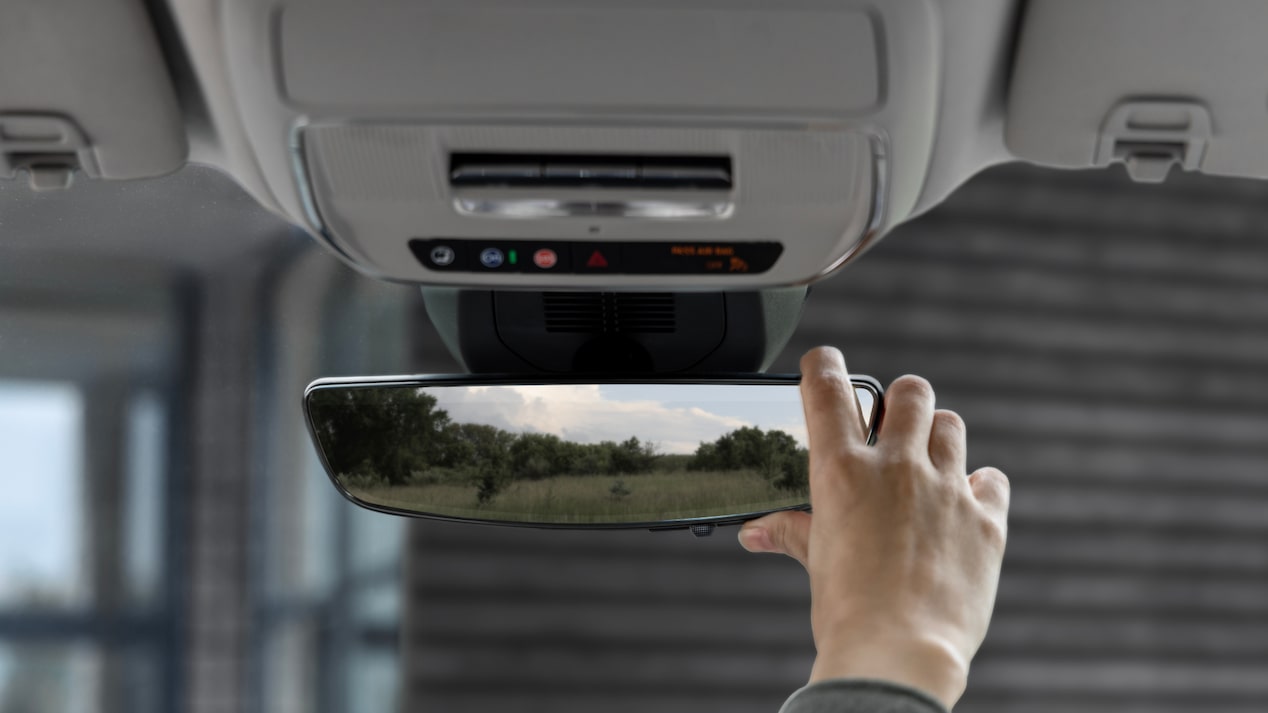 A person's hand adjusting the rearview mirror on the 2025 GMC Terrain.
