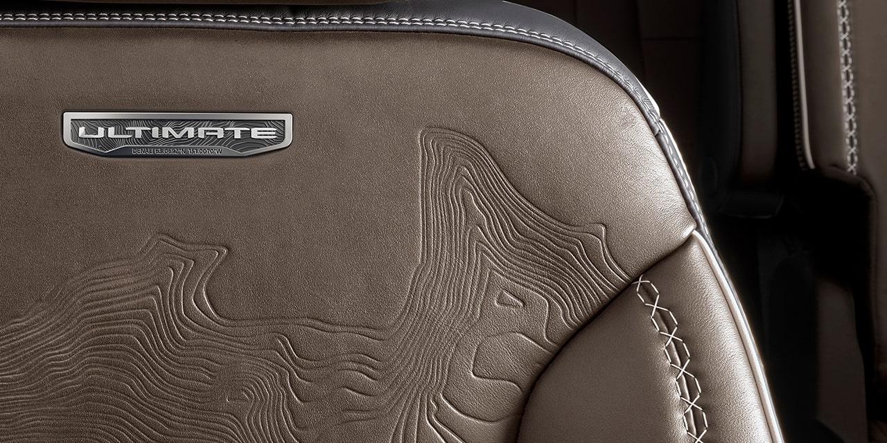 Vue rapprochée de l’emblème gravé sur les sièges en cuir du GMC Acadia Denali Ultimate 2026.