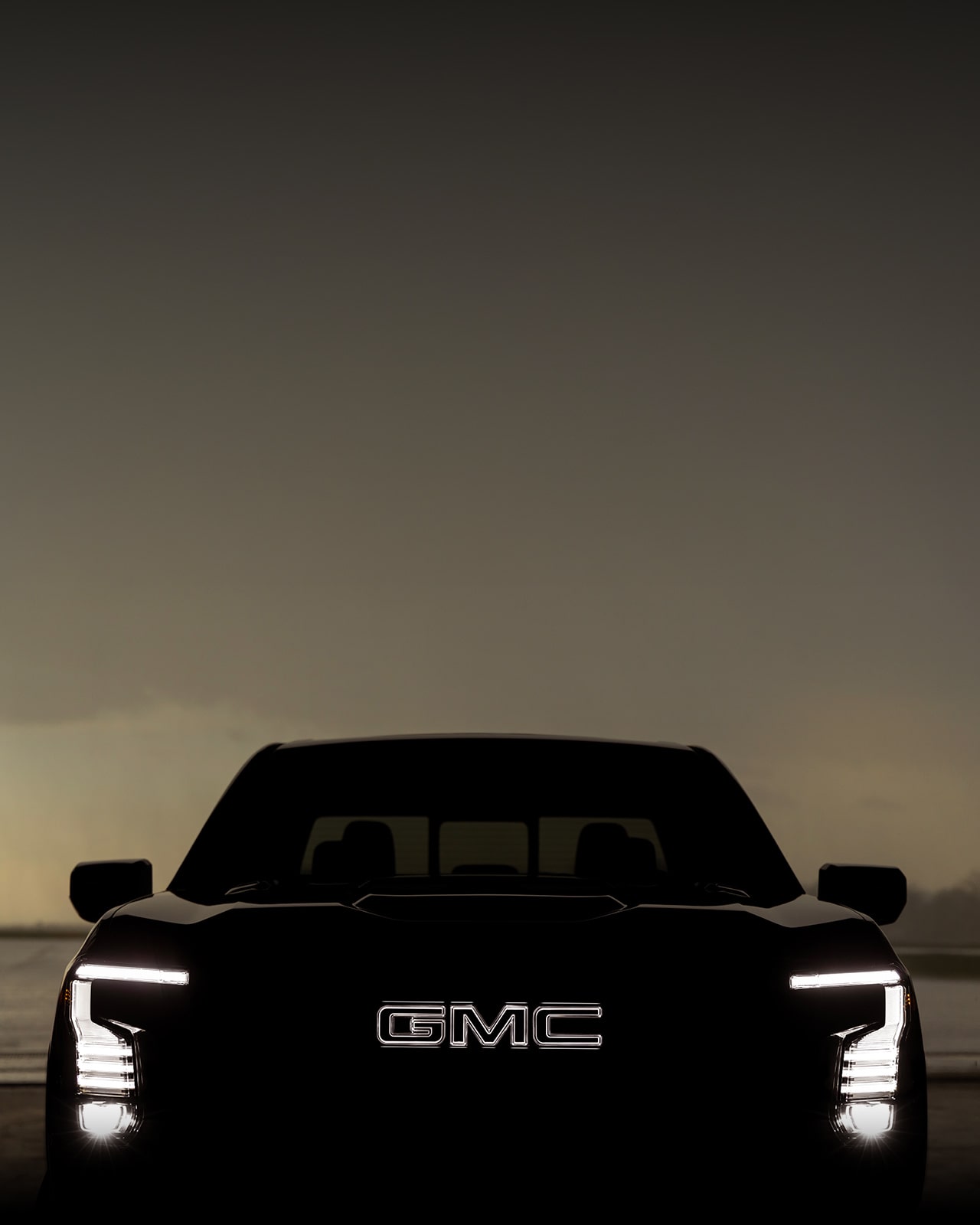 Front-view of GMC Sierra 1500 with the lights on and the logo illuminated.  