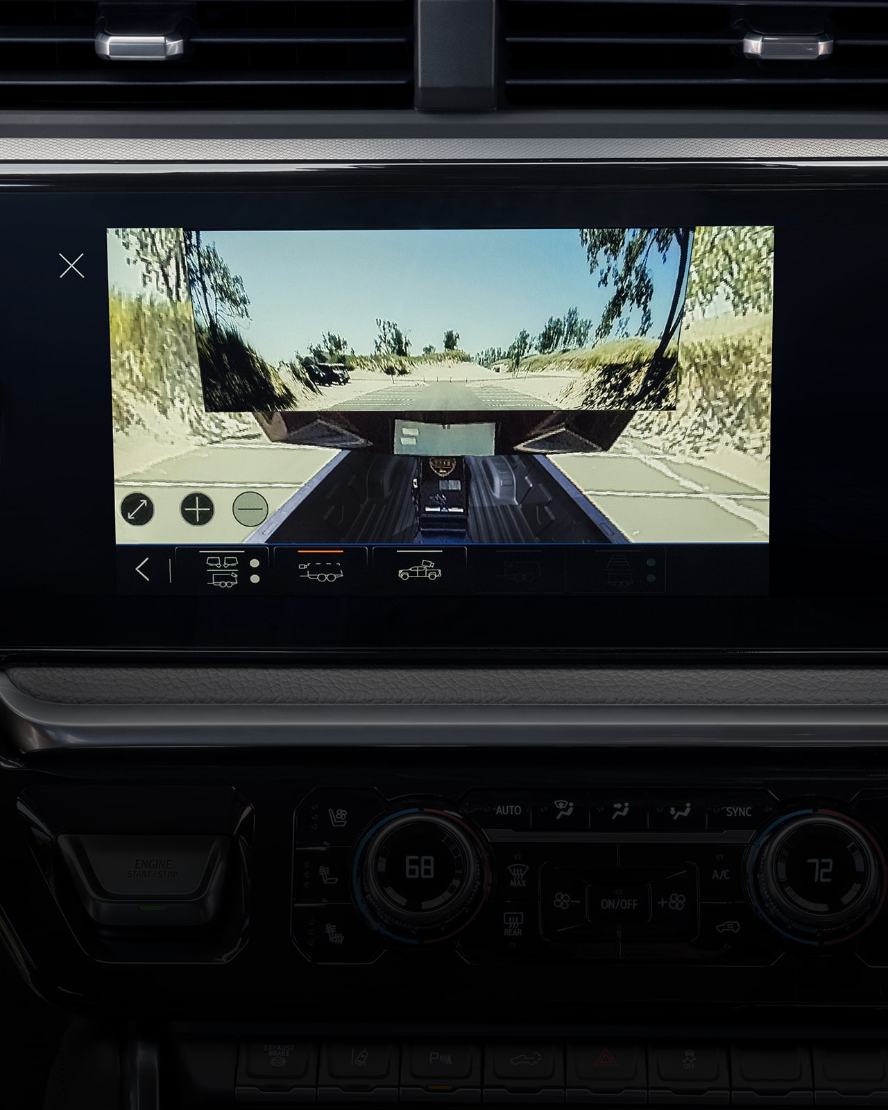 Tableau de bord du GMC Sierra HD 2027 avec grand écran d’infodivertissement affichant la vue d’une caméra de remorque sur une route sinueuse.