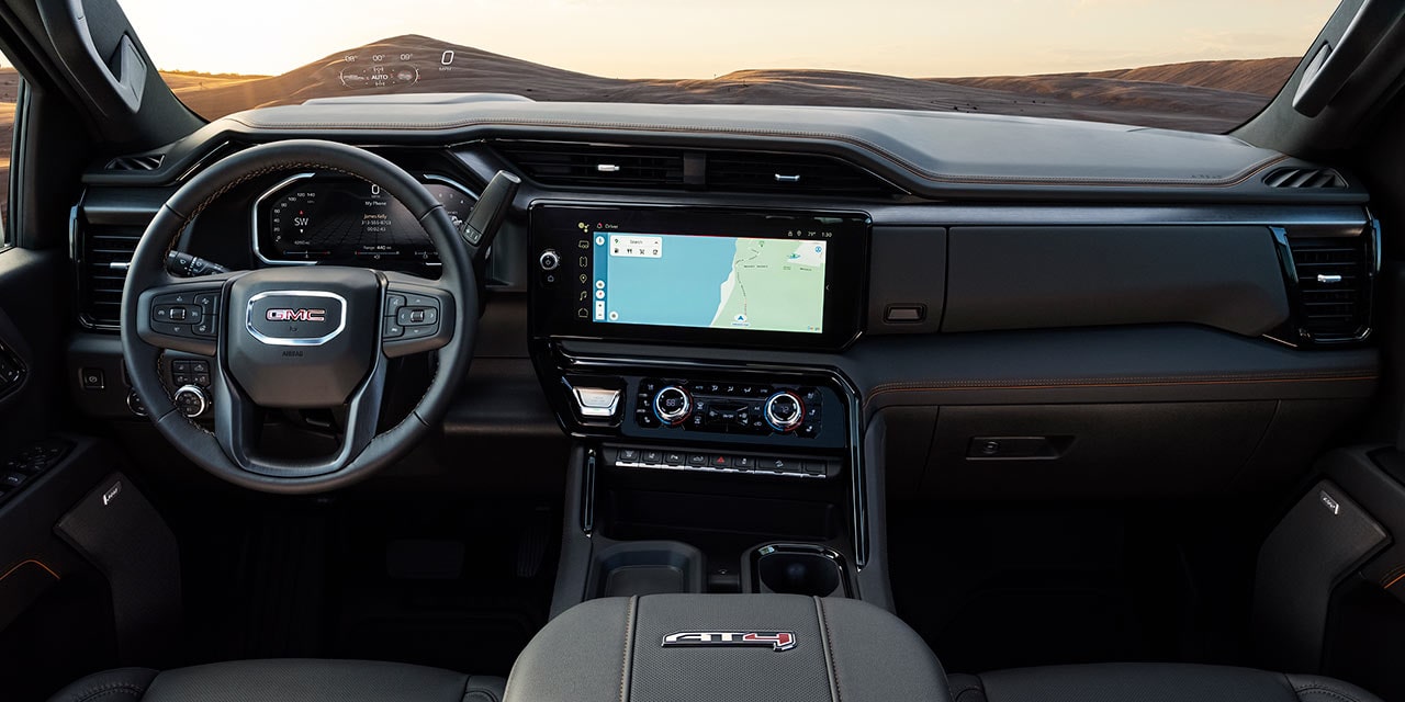 Tableau de bord du GMC Sierra HD AT4X avec volant et écran d’infodivertissement affichant une carte.