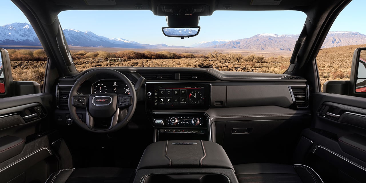 Tableau de bord et volant du GMC Sierra HD 2027 avec des montagnes visibles par le pare-brise.