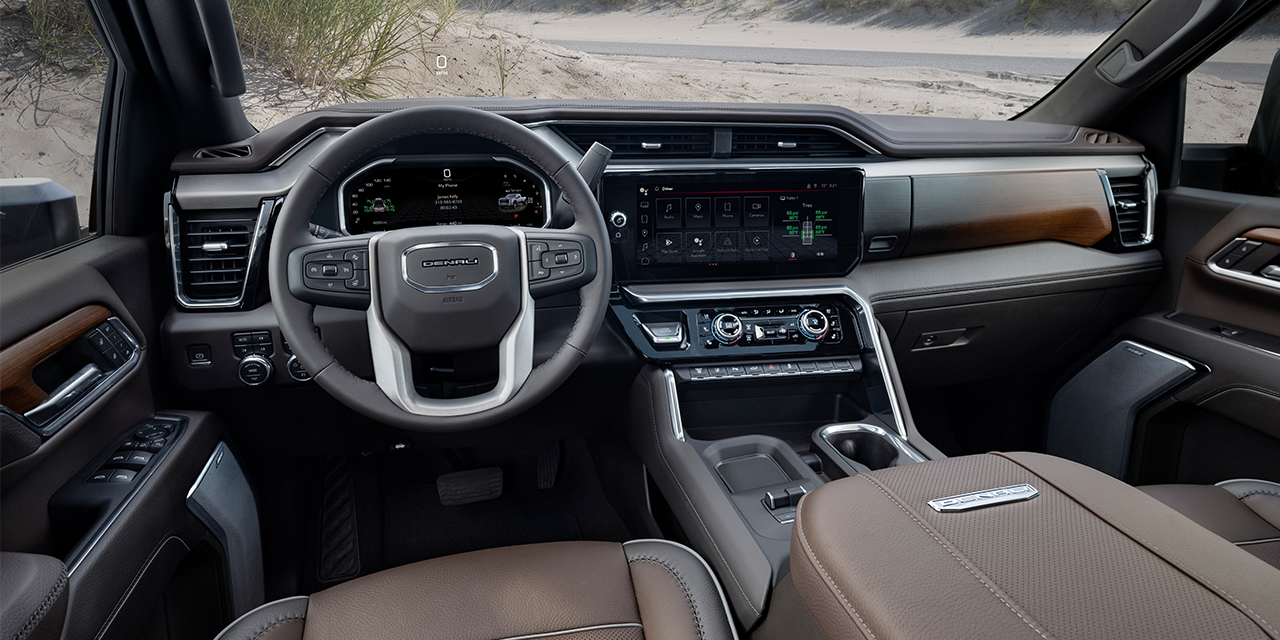 Intérieur du GMC Sierra HD 2027 avec sièges en cuir brun et vue sur le désert par les fenêtres.
