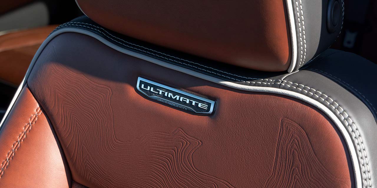 Gros plan d’un siège en cuir brun du GMC Sierra HD Denali Ultimate avec motif topographique.