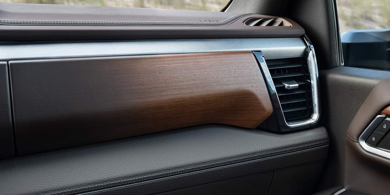 Gros plan d’une garniture en bois brun et d’une bouche d’aération sur le tableau de bord d’un GMC Sierra HD.