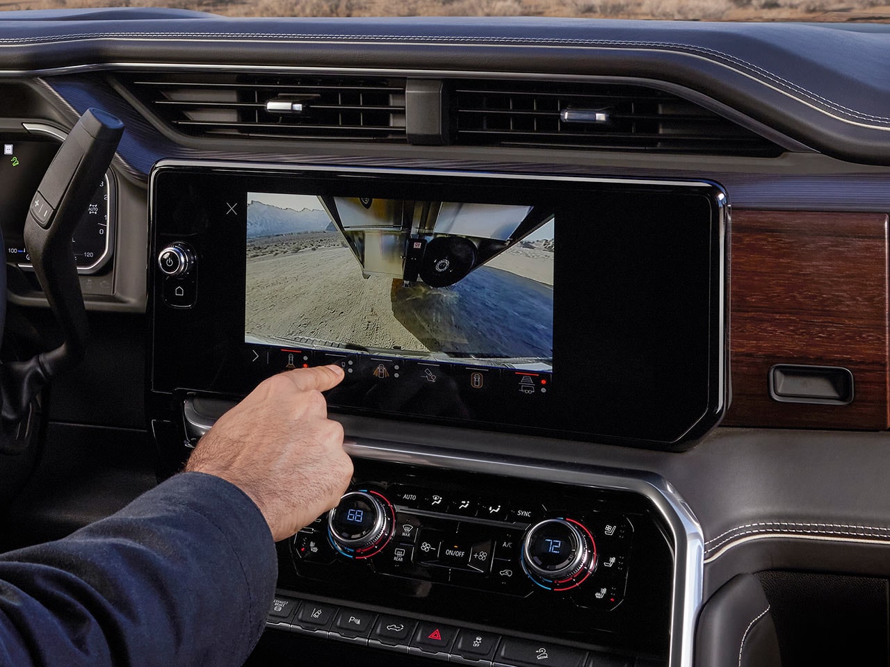 Écran d’infodivertissement du GMC Sierra HD 2027 affichant la vue d’une caméra de remorque pendant qu’une main utilise l’écran.