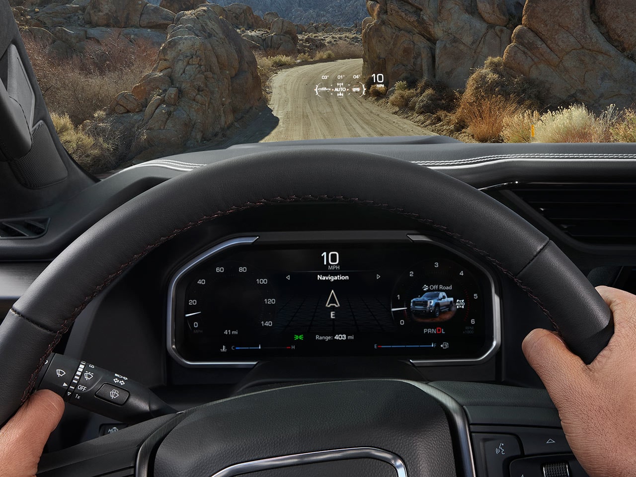 Tableau de bord du GMC Sierra HD 2027 avec mains sur le volant et bloc d’instruments numérique affichant la navigation.