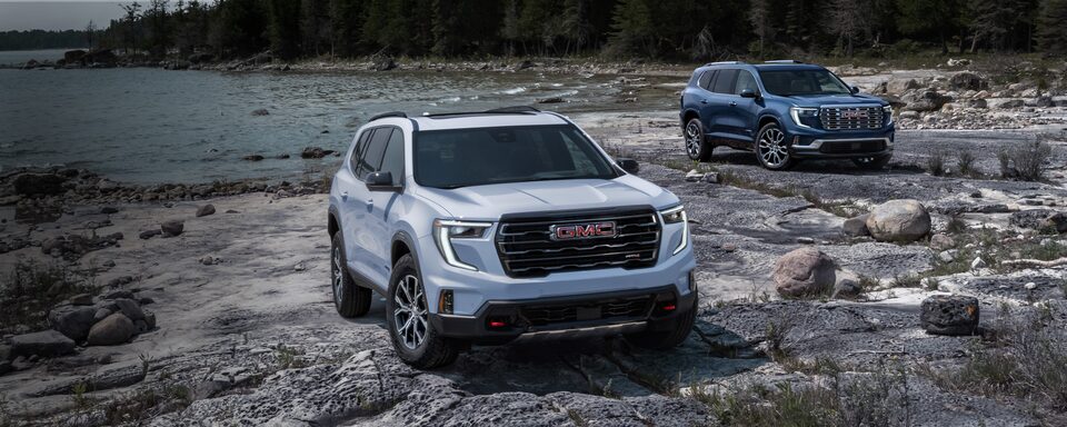 Deux modèles GMC Acadia 2024 stationnés au bord d’un lac.