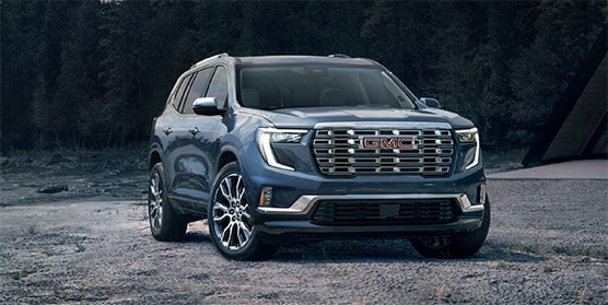 Front view of the 2025 GMC Acadia Denali parked alone outdoors in a gloomy weather.