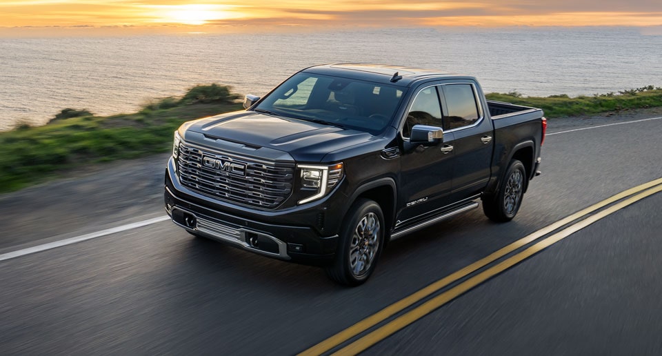 GMC Truck Driving on a Road by a Lake
