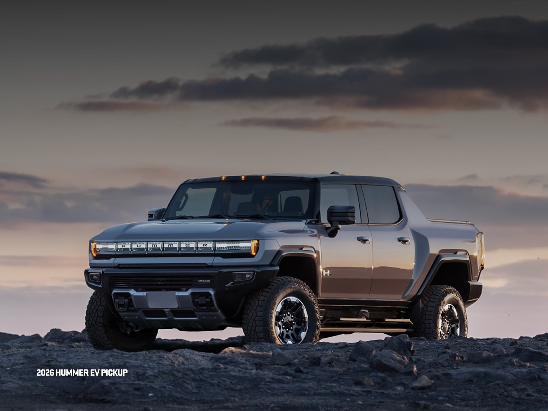 Vue latérale avant du VUS GMC Hummer EV 2026 en mouvement seul sur la route.