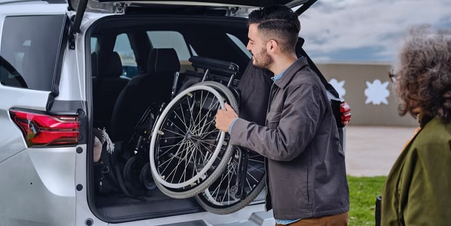 Un homme transporte un fauteuil roulant pour une personne admissible au programme Mobilité de GM.