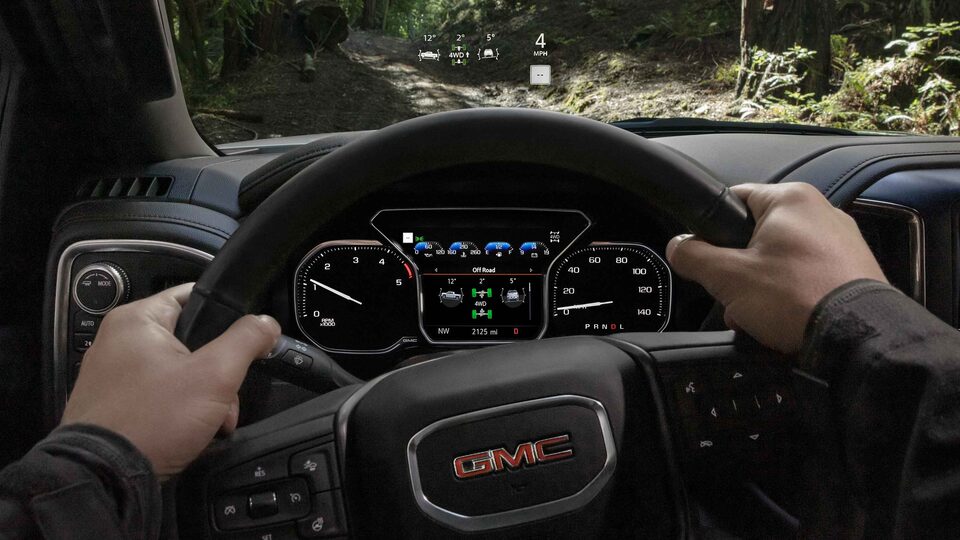 Man holding the steering wheel of a 2021 Sierra HD AT4.