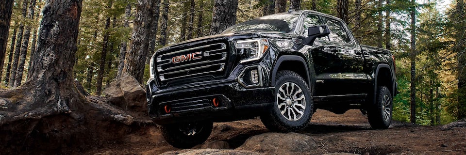 Front side view of the 2021 GMC Sierra AT4 parked in a wooded area.