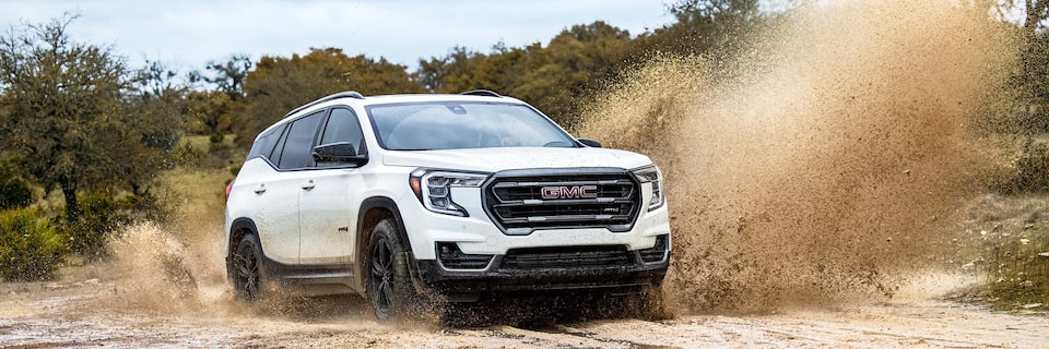 The 2024 Sierra AT4 driving on a dusty road.