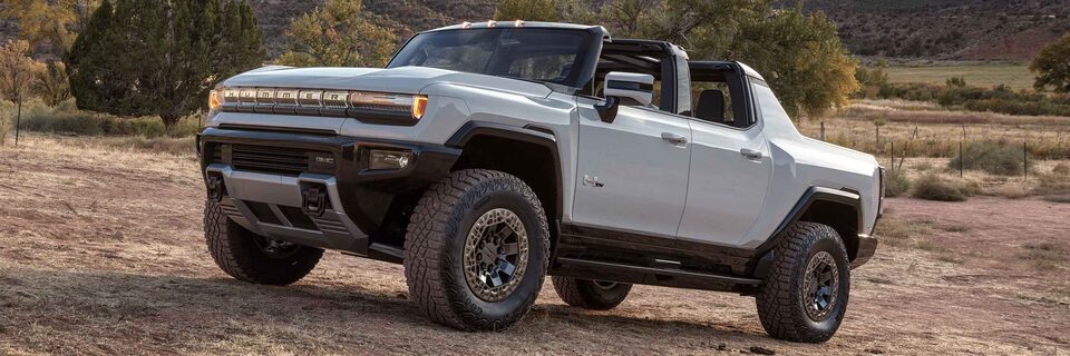 2023 GMC Hummer EV driving on an arid terrain.