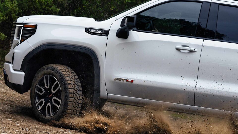 Exterior driver-side view of the 2023 Sierra 1500 AT4 driving off-road.