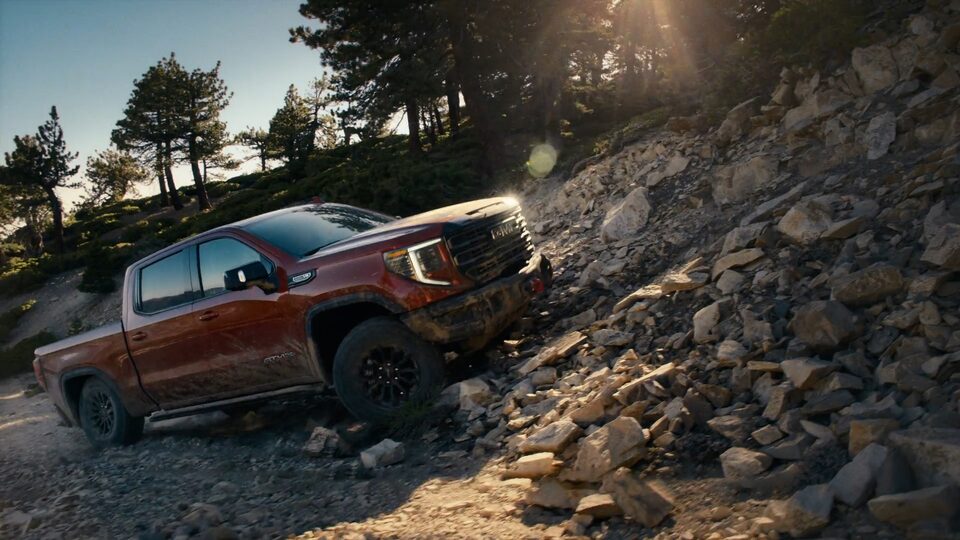 The 2023 Sierra 1500 AT4X driving over rocky terrain.